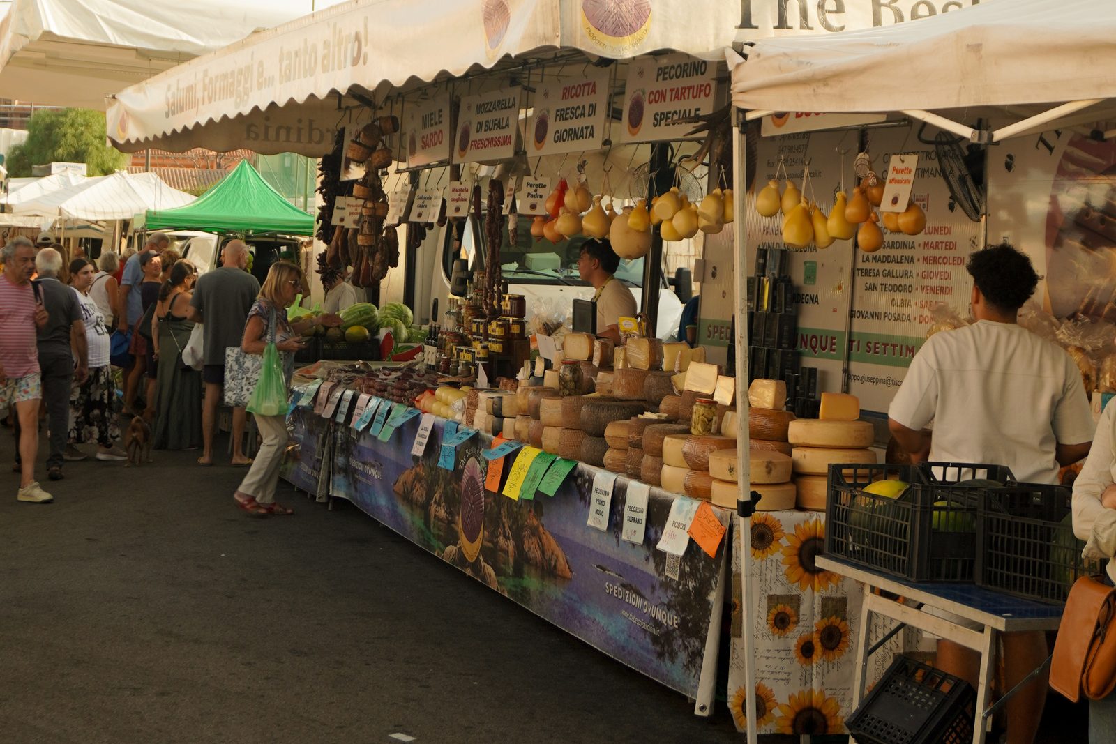 Panoramica del banco The Best of Sardinia allestito al mercato, con clienti e prodotti in mostra